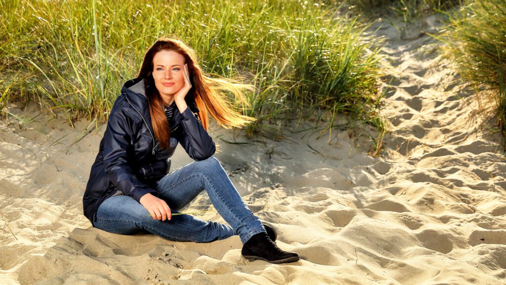 Hübsche Frau sitzt in den Dünen am Strand